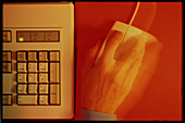 Hand operates a computer mouse beside a keyboard