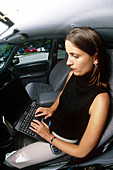 Woman on laptop inside her car