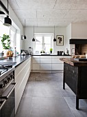 weiße Küchenzeile übereck, schwarze Pendelleuchten und Kücheninsel aus alter Werkbank