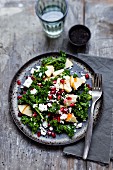 A curly kale salad with pomegranate seeds, sheep's cheese and apple slices