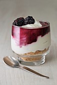 Blackberry cheesecake made withcream cheese, cream, blackberry coulis and crushed biscuits served in a glass