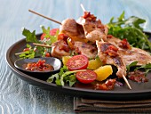 Chicken kebabs on a bed of rocket and tomato salad
