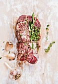 Raw uncooked roastbeef meat cut with rosemary, thyme and garlic on old white painted wooden background