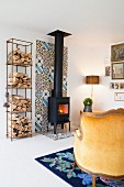Firewood on shelves next to wood-burning stove on strip of colourful tiles on wall and floor