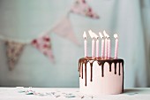 Geburtstagstorte mit Schokoglasur und rosa Kerzen