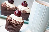 Cupcakes decorated with black cherries and chocolate shavings