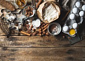 Zutaten für die Weihnachtsbäckerei: Gewürze, Mehl, Eier, Kakaopulver, Zucker, Honig und Nüsse und Ausstecher auf rustikalem Holzuntergrund