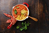 Spaghetti Bolognese mit frischem Basilikum in einer Pfanne auf Holzuntergrund