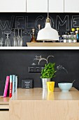 Kitchen counter with chalkboard splashback and white wall-mounted shelf