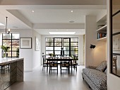 Open-plan interior with white floor, dining area and sofa in niche