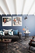 Couch, table and large photos on blue-grey wall in lounge area