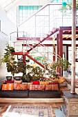 Gemütlicher Loungebereich mit orangefarbenen Kissen vor Treppe in Loftwohnung mit Glasfassade