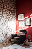 Black leather armchair and carved wooden snake in front of stone wall abutting red wall