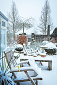 Garten im Winter mit Schneedecke und Holzmöbeln