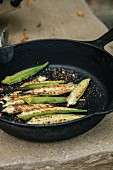 Fried okra halves in a cast iron pan