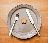 A symbolic image for dieting: a plate with cutlery and a tiny slice of toast