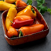 Yellow, red and orange peppers in a clay bowl