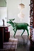 Green stag sculpture below capiz-shell lamp in living room