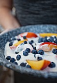 A woman holding a yoghurt dessert with blueberries and peach