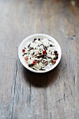 A wild rice mixture with red peppercorns in a bowl