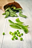 Peas and their pods on a wooden surface