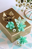 Origami flowers on gift wrapped in gold paper