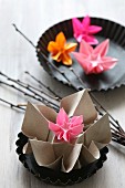 Colourful origami flowers in round tart tins