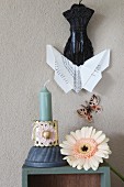 Origami butterfly held in clip above gerbera daisy and candle