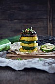 A vegan tower made of polenta rounds and slices of courgette with porcini mushrooms