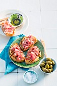 Grilled tomato bread with serrano ham and green olives