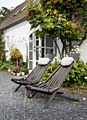 Klappbare Liegestühle aus Holz im Garten vor dem Haus