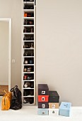 Many shoes in tall, narrow shoe cabinet next to stacked shoeboxes