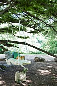 DIY-Schaukelbrett mit Kissen und Fransendecke an Baum aufgehängt