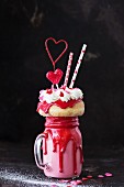 A Valentine's Day freak shake with a mini doughnut and a heart-shaped lolly