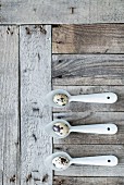 Quail eggs on three metal spoons on weathered wooden surface