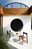 Various chairs on veranda with black circle on wall