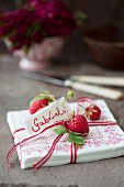 Napkins with a ribbon, strawberries and a name tag