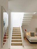 Heller Wohnraum mit weißer Treppe und einer Recamiere