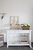 Old window frame, birdcage and flowers on white console table