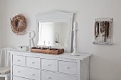 Old mirror on white-painted chest of drawers