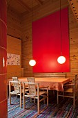 Red artwork and illuminated spherical lamps in high-ceilinged dining room in wooden house