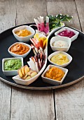 Raw vegetables with assorted vegetable dips on a serving dish