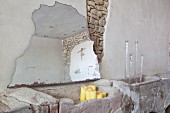 Fragment of mirror leaning against wall, candlesticks and candles in rustic interior