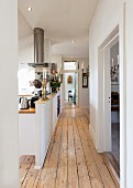 Flur mit Holzdielen und offener Küche hinter halbhoher Wand