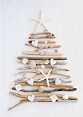 Christmas tree formed from driftwood and pebbles on white surface