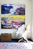 Fur blanket on old swivel chair and treasure chest below abstract artwork on wall