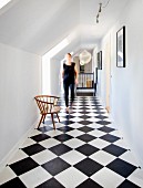 Black and white chequered floor in attic corridor with woman in background