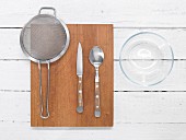 Kitchen utensils: colander, knife, spoon and glass bowl