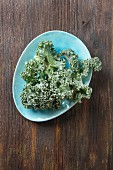 Fresh kale leaves on a blue plate on a wooden surface