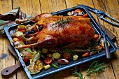 Roast goose with vegetables on an oven tray